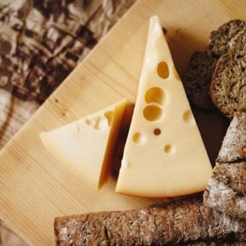 Sliced gruyere cheese on a brown table top.