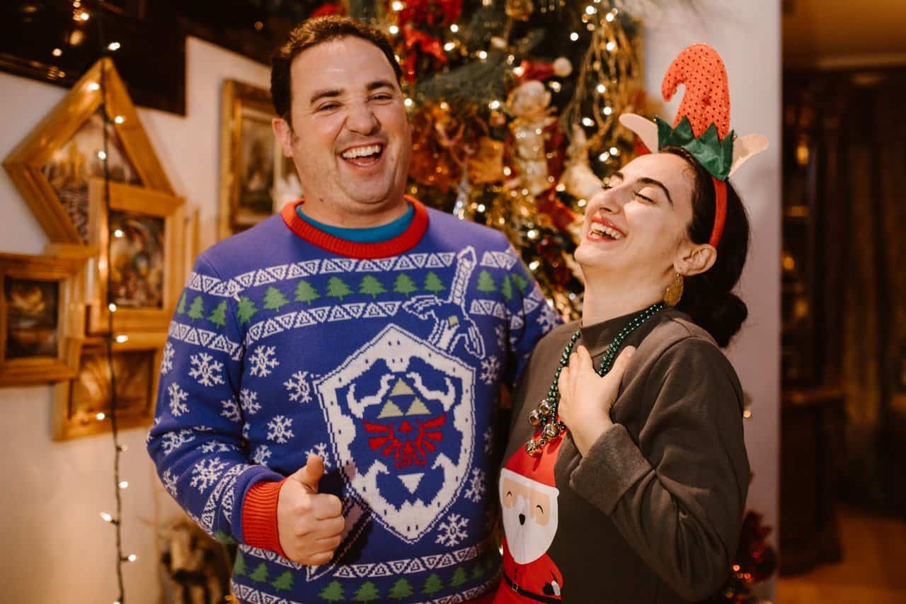 Two people in Christmas sweaters laughing together.