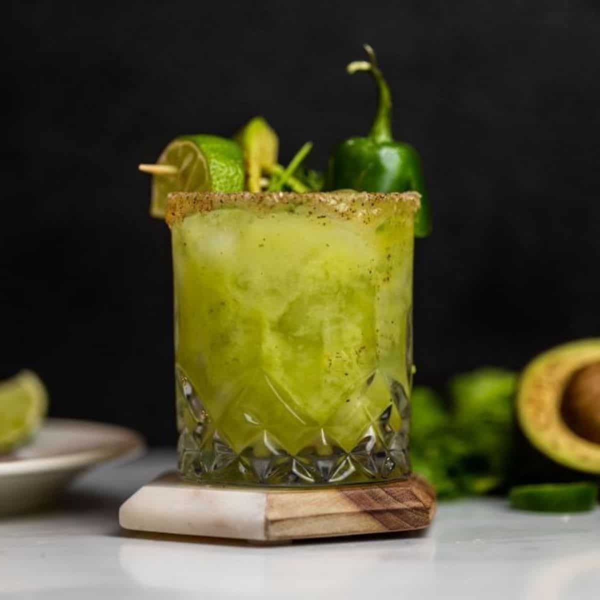 Avocado margarita on table with cilantri and jalapeno pepper.