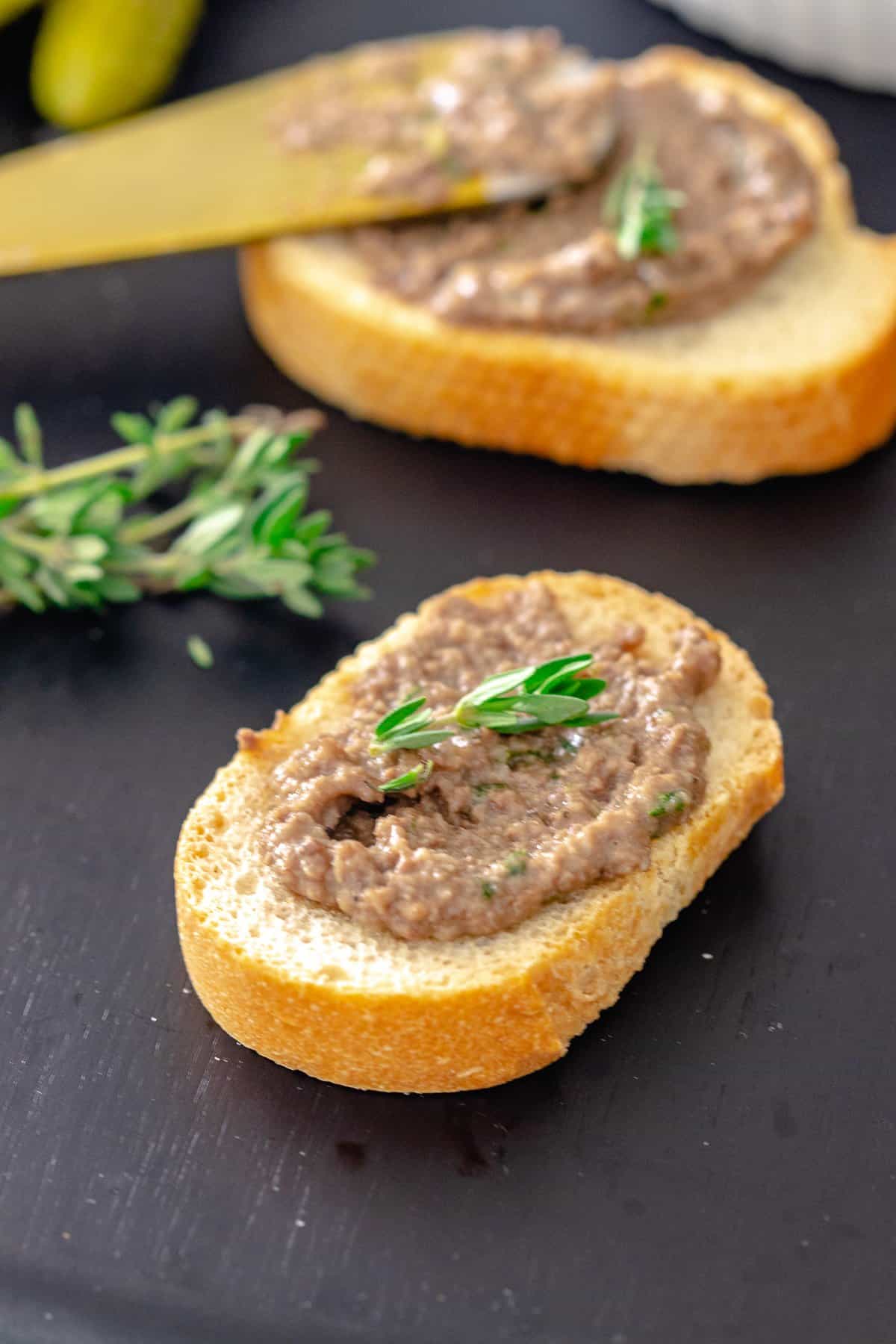 Chicken liver pate served on toast with thyme sprig.