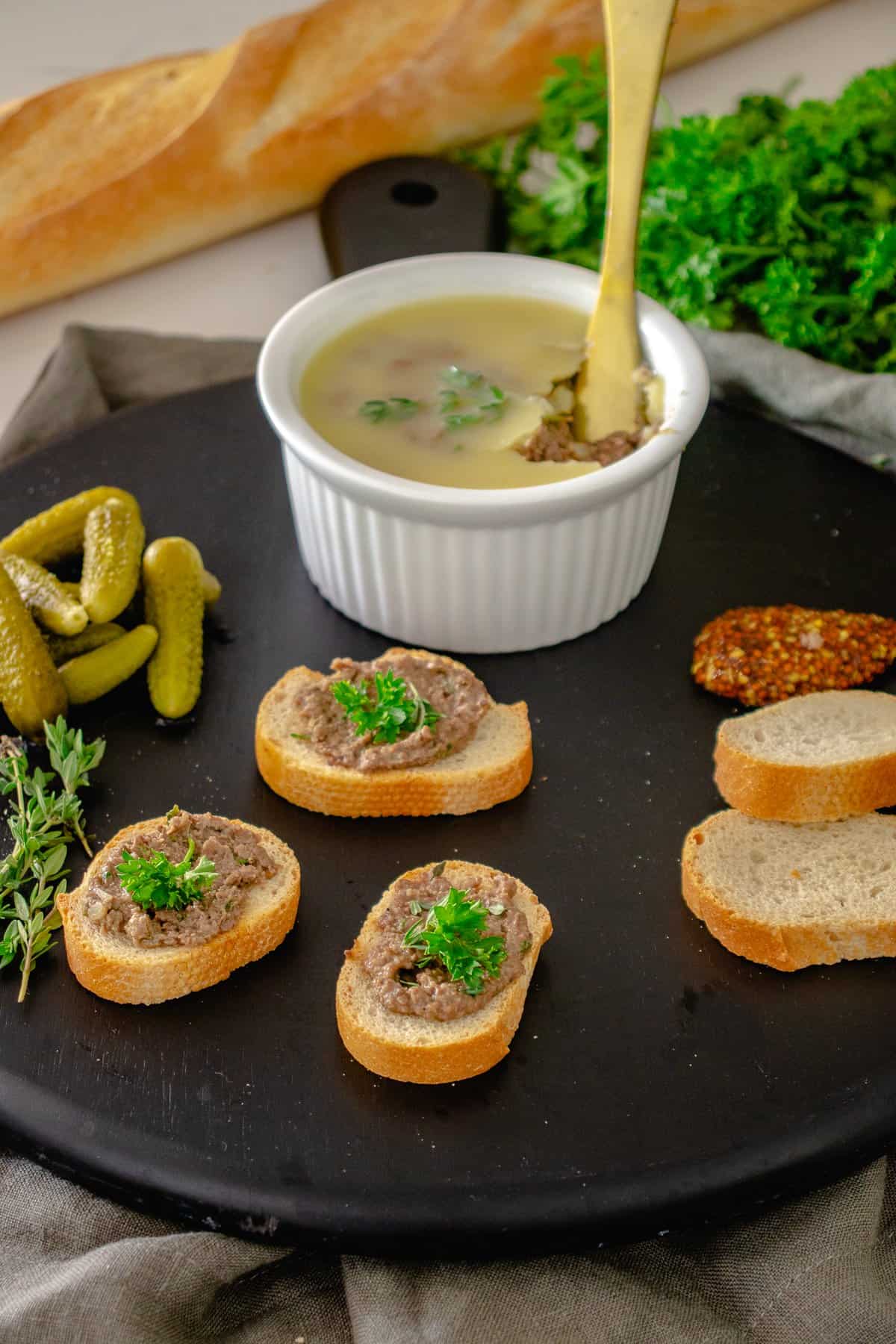 Pate in a ramekin on table with crostini.