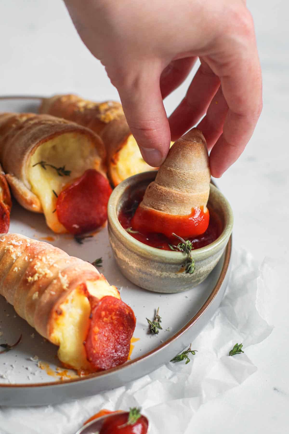 Dipping pizza cones into marinara sauce.