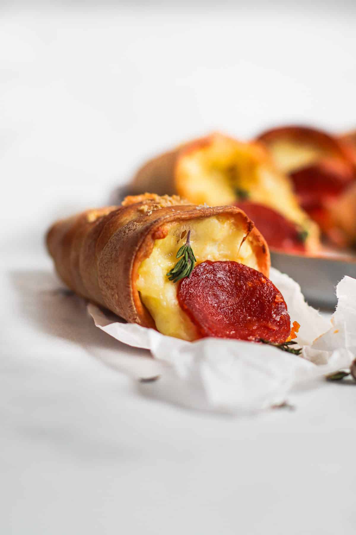 Pizza cones on sheet pan with cheese oozing out.