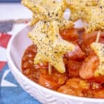 Kielbasa sliced in bowl with sauce and toothpick stars.