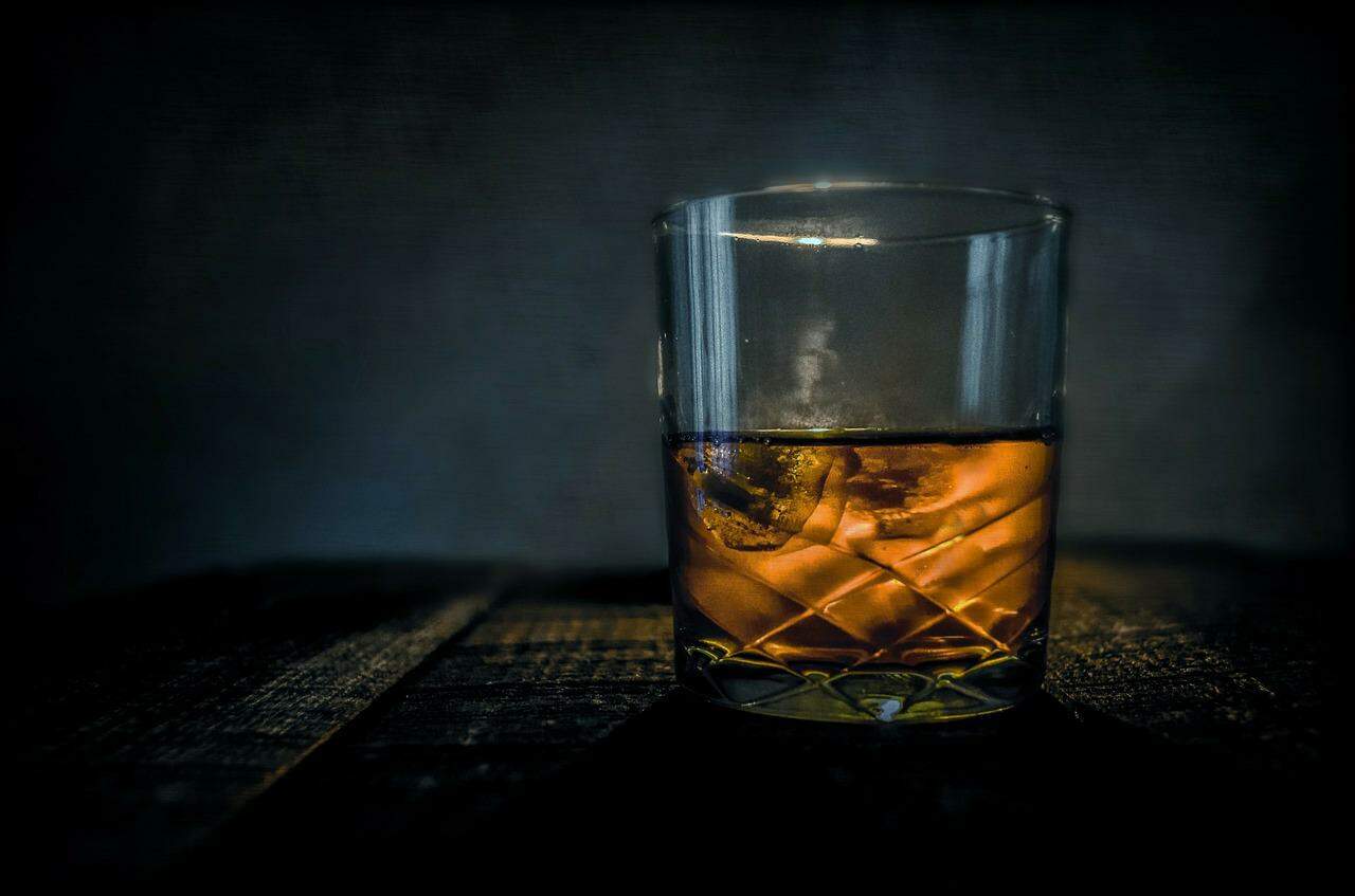 A glass of whiskey sitting on a table.