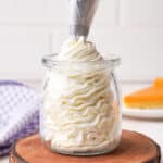 Piping bourbon whipped cream into a clear glass.