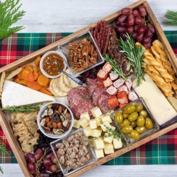 Charcuterie board with cheese knife and glass.