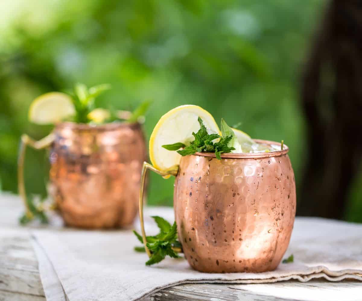 A moscow mule on table with lemon wheel and mint.