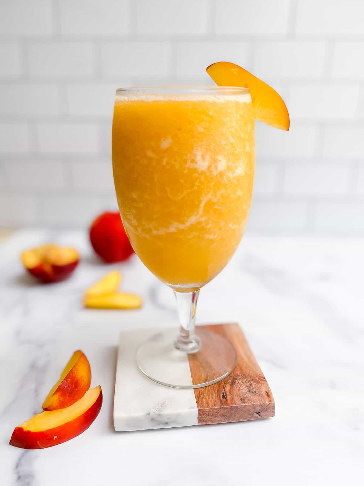 Peach frosé on a table with peach slice.