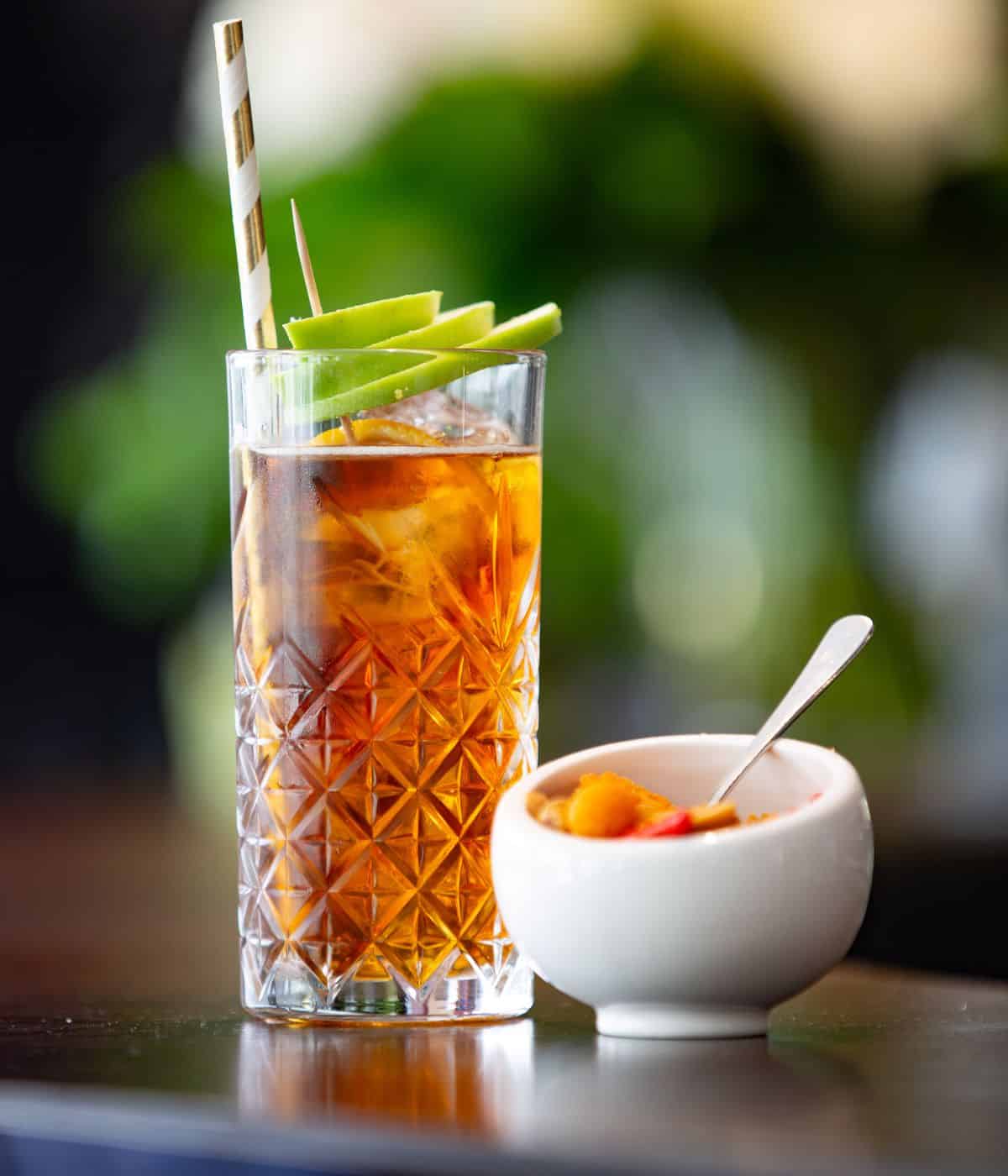 A highball glass with a cocktail and garnish.