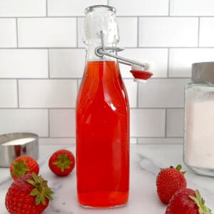 Bottle of homemade strawberry simple syrup.