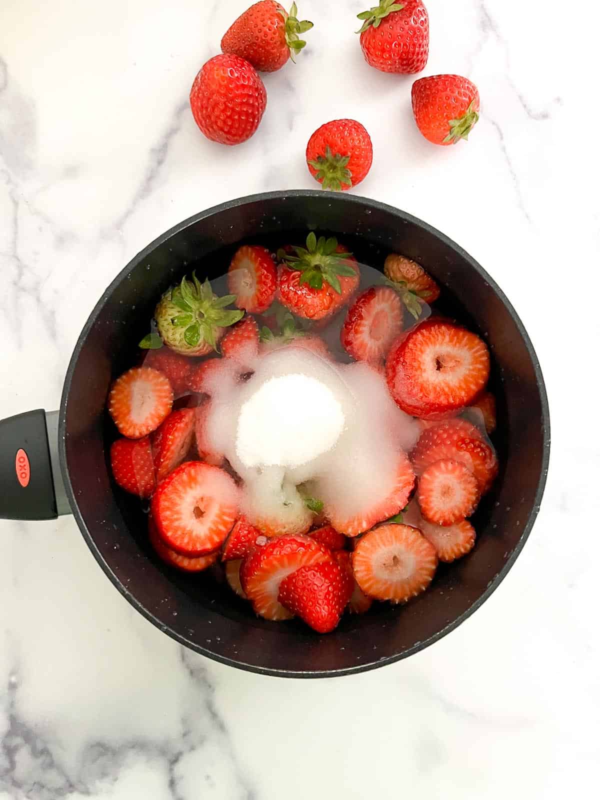 Strawberries and sugar in a saucepan with water.