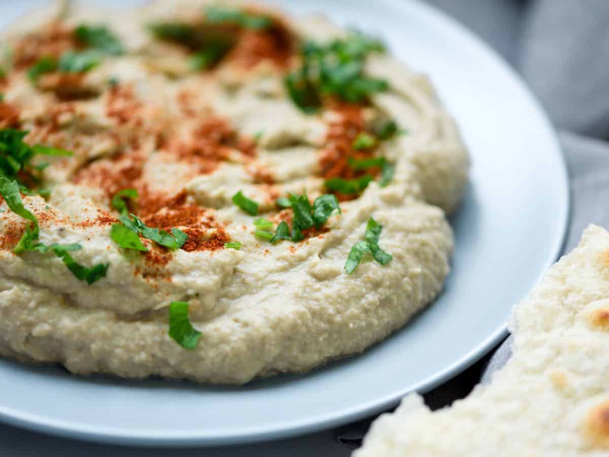 Closeup of whipped eggplant dip on a plate with herbs and paprika on top.