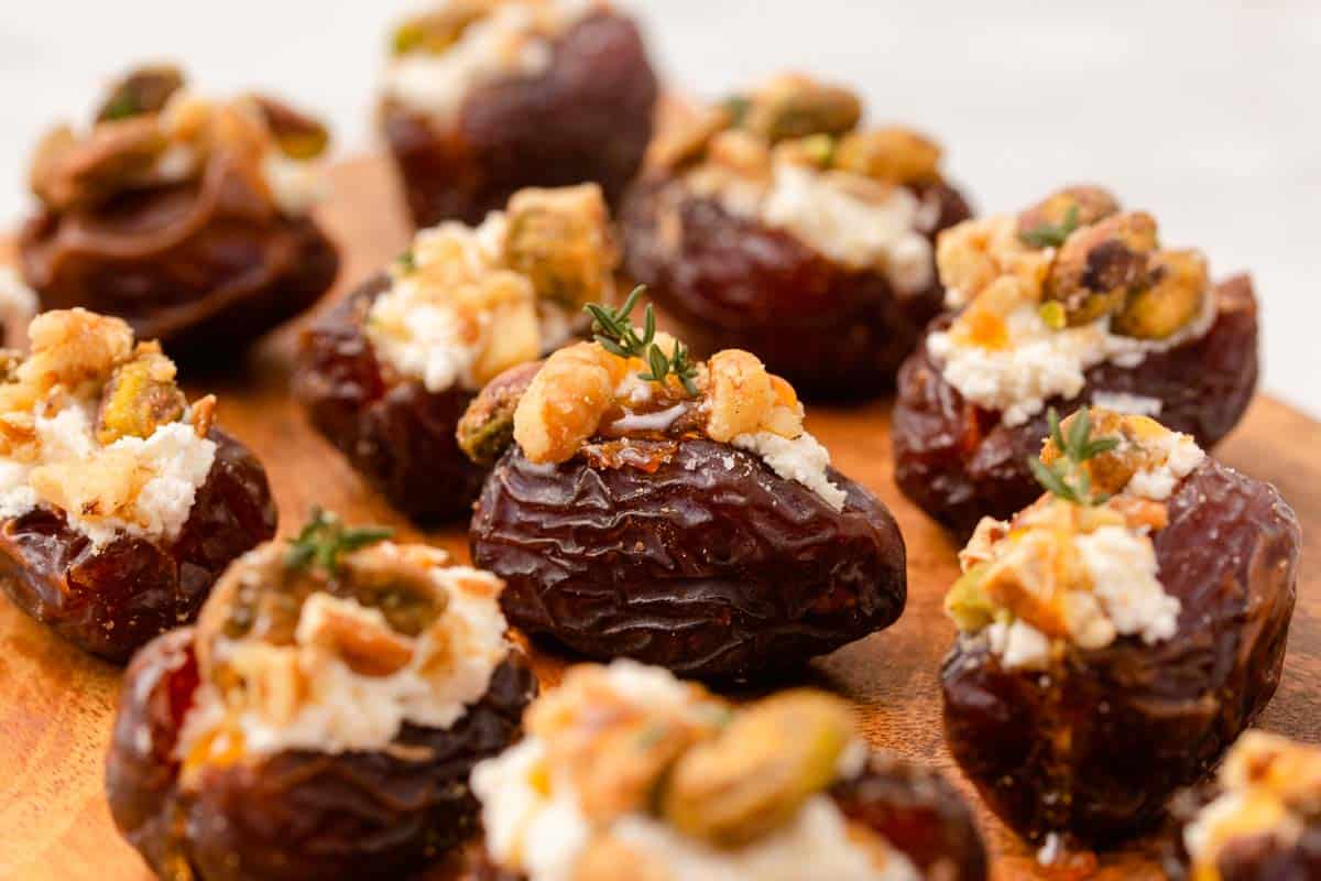 Stuffed dates on table with pecan and thyme leaves on top.