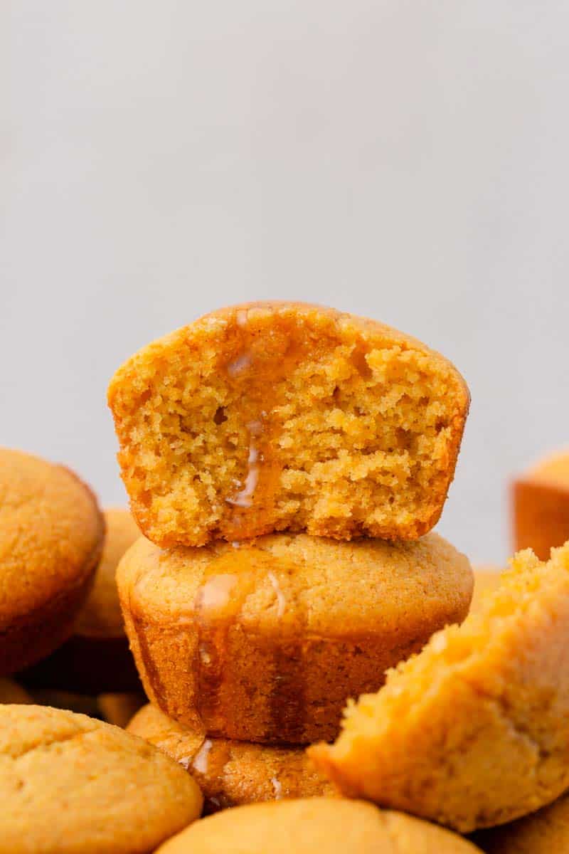 Mini sweet cornbread muffins stacked with honey dripping down.