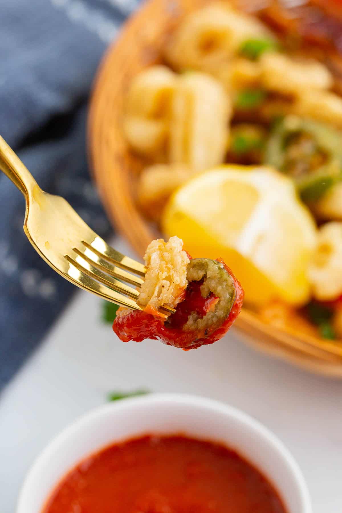 Calamari rings on fork dipped in marinara sauce.