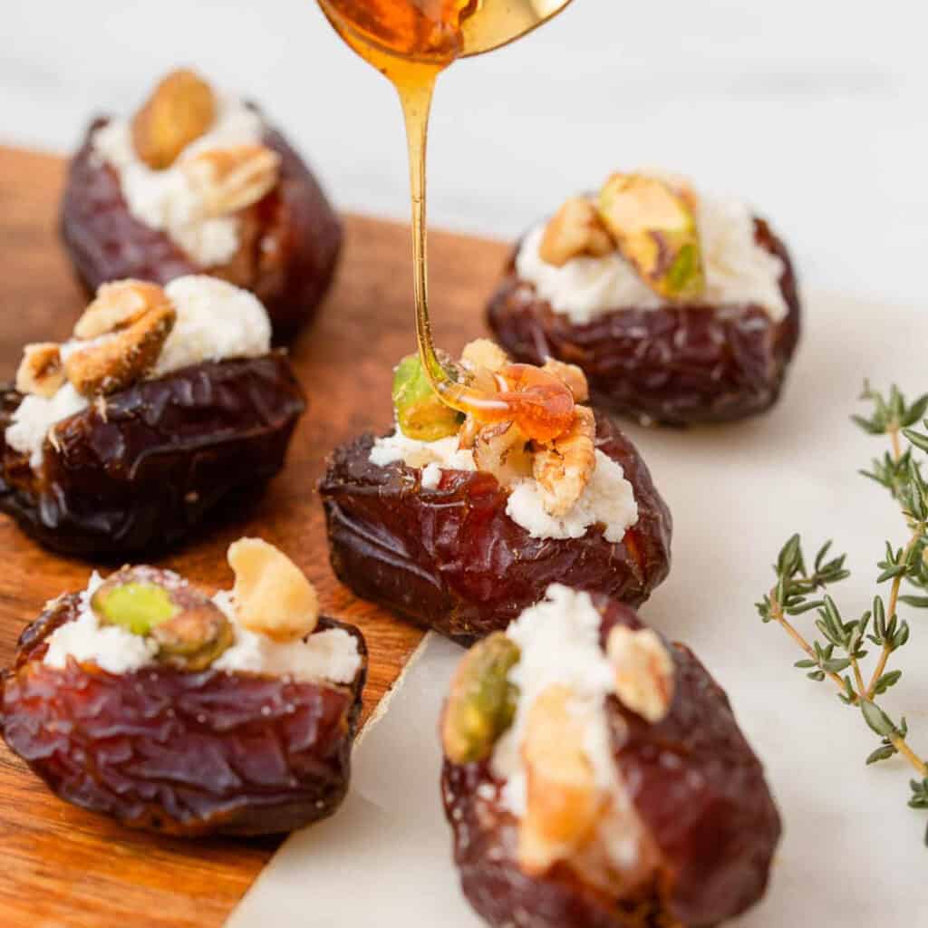 Stuffed dates drizzled with honey on table.