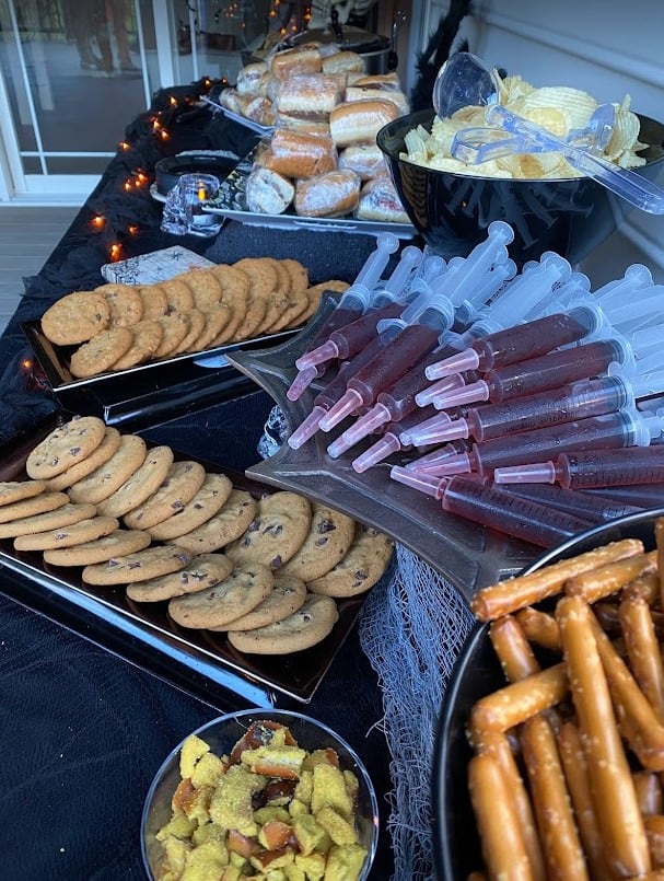 Food table with jello shots, desserts and snacks for party.