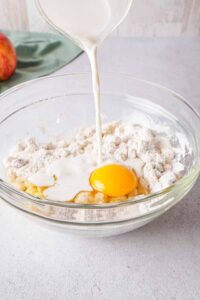 Pouring milk into apple fritter bowl.