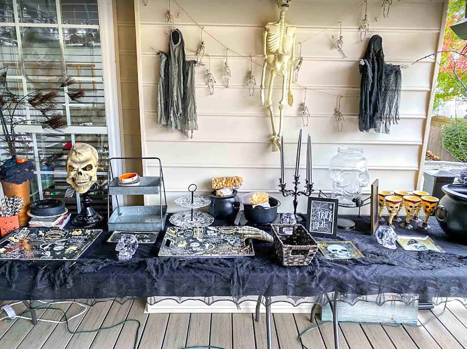 Outdoor table decorated for Halloween with food and spooky decorations.