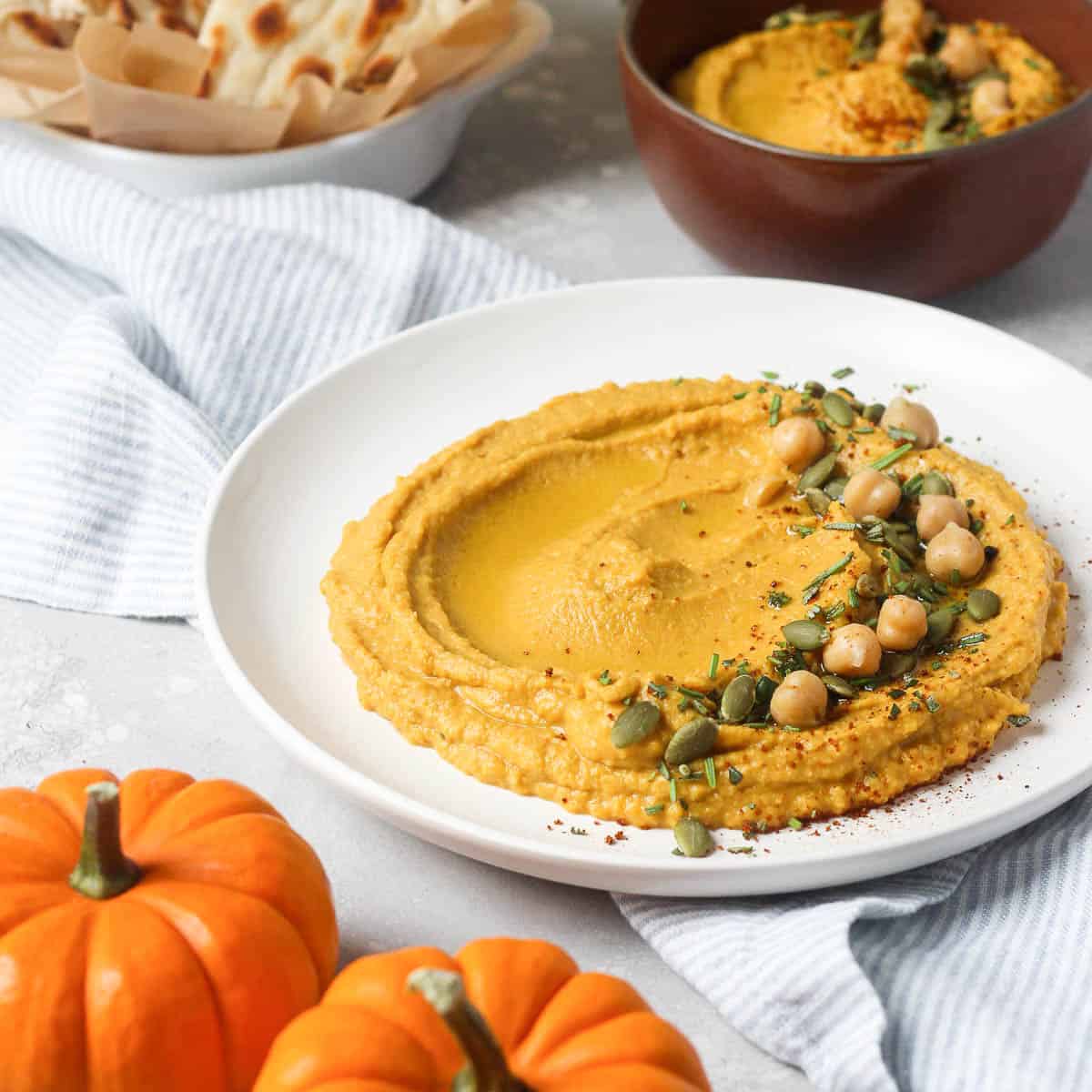 Pumpkin hummus on white plate with chick peas.