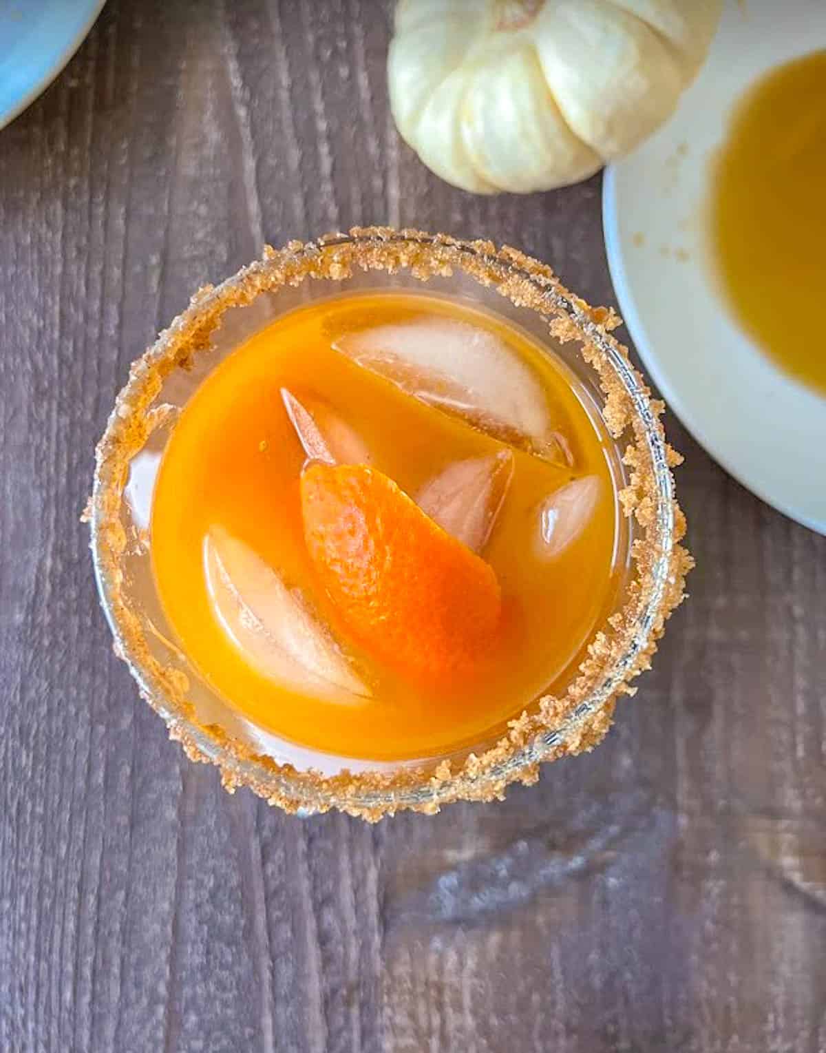 Pumpkin pie margarita with ice cube and orange peel.