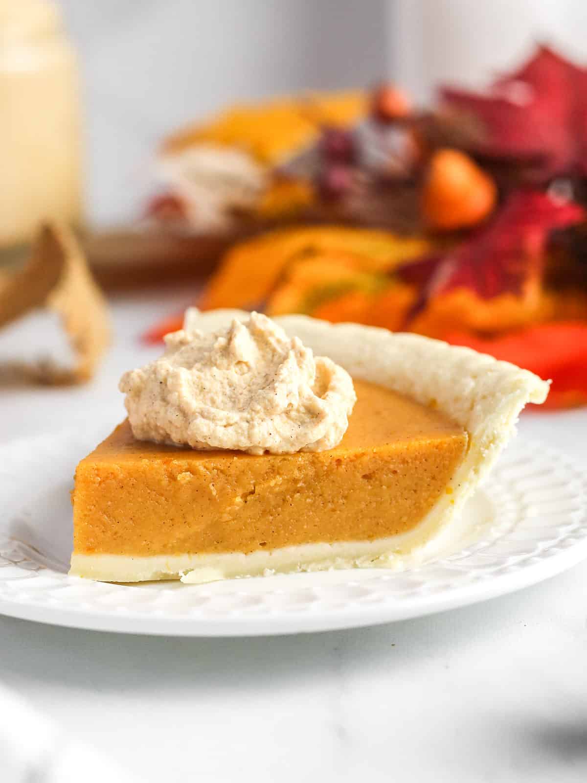 A dollop of pumpkin whipped cream on top of pumpkin pie.