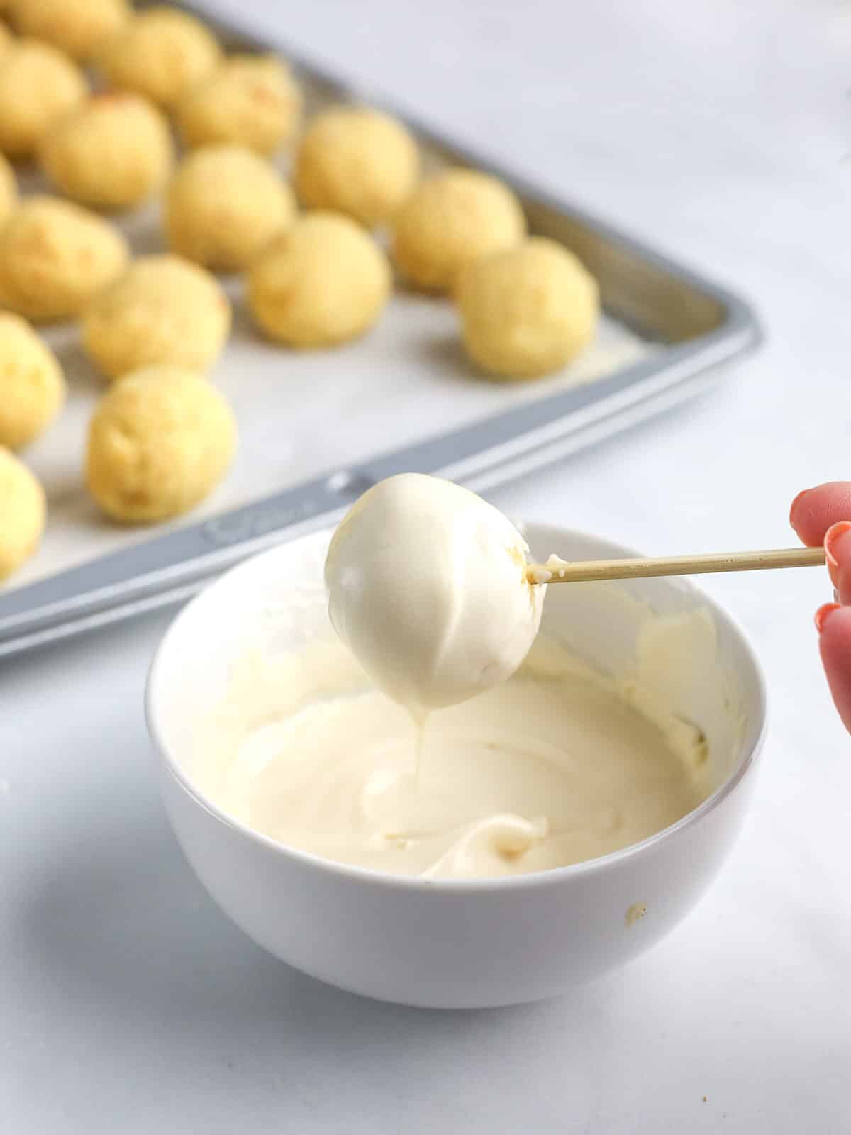 Coating cake balls with white chocolate.