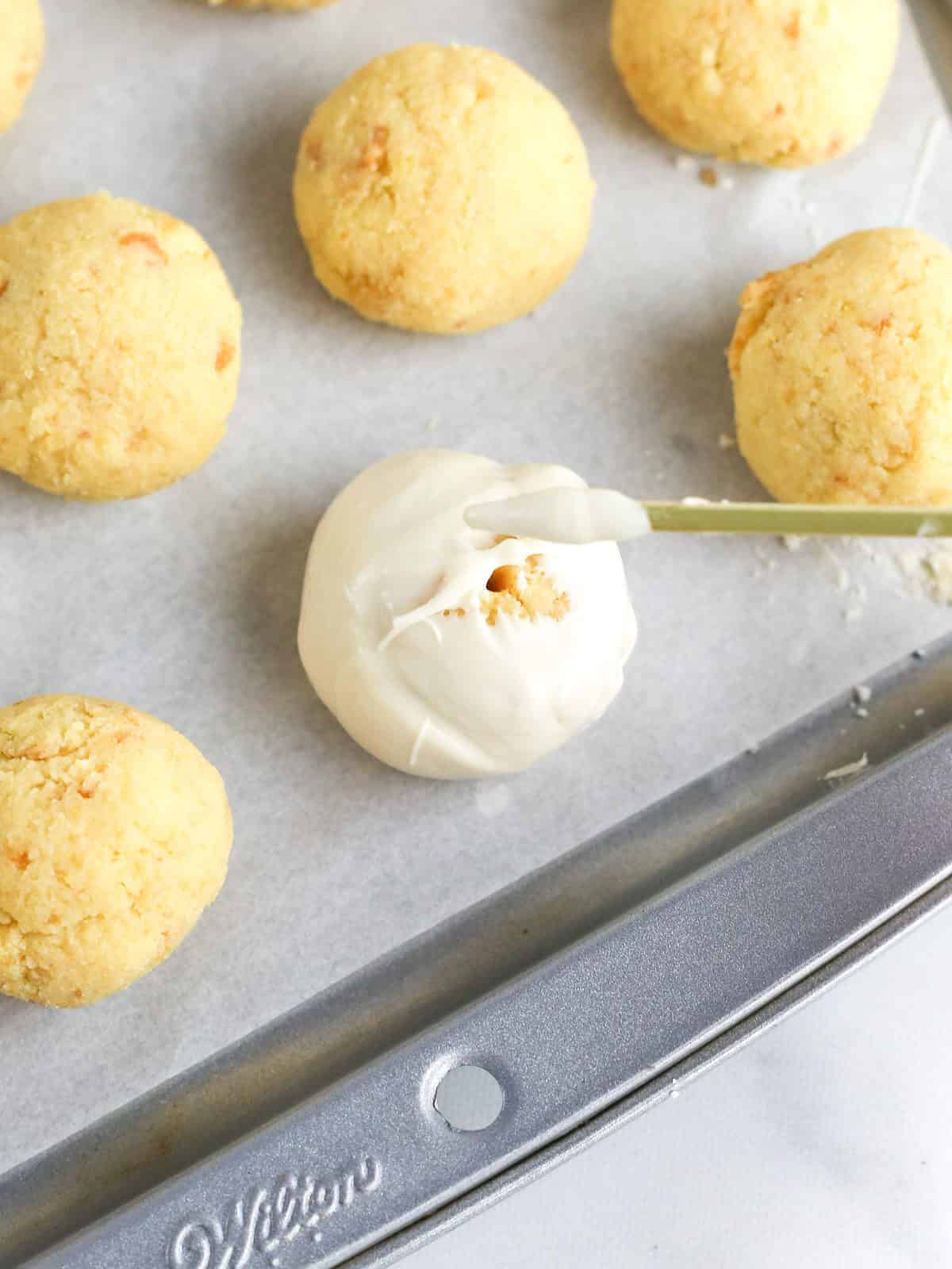 Patching up hole in cake ball with chocolate.