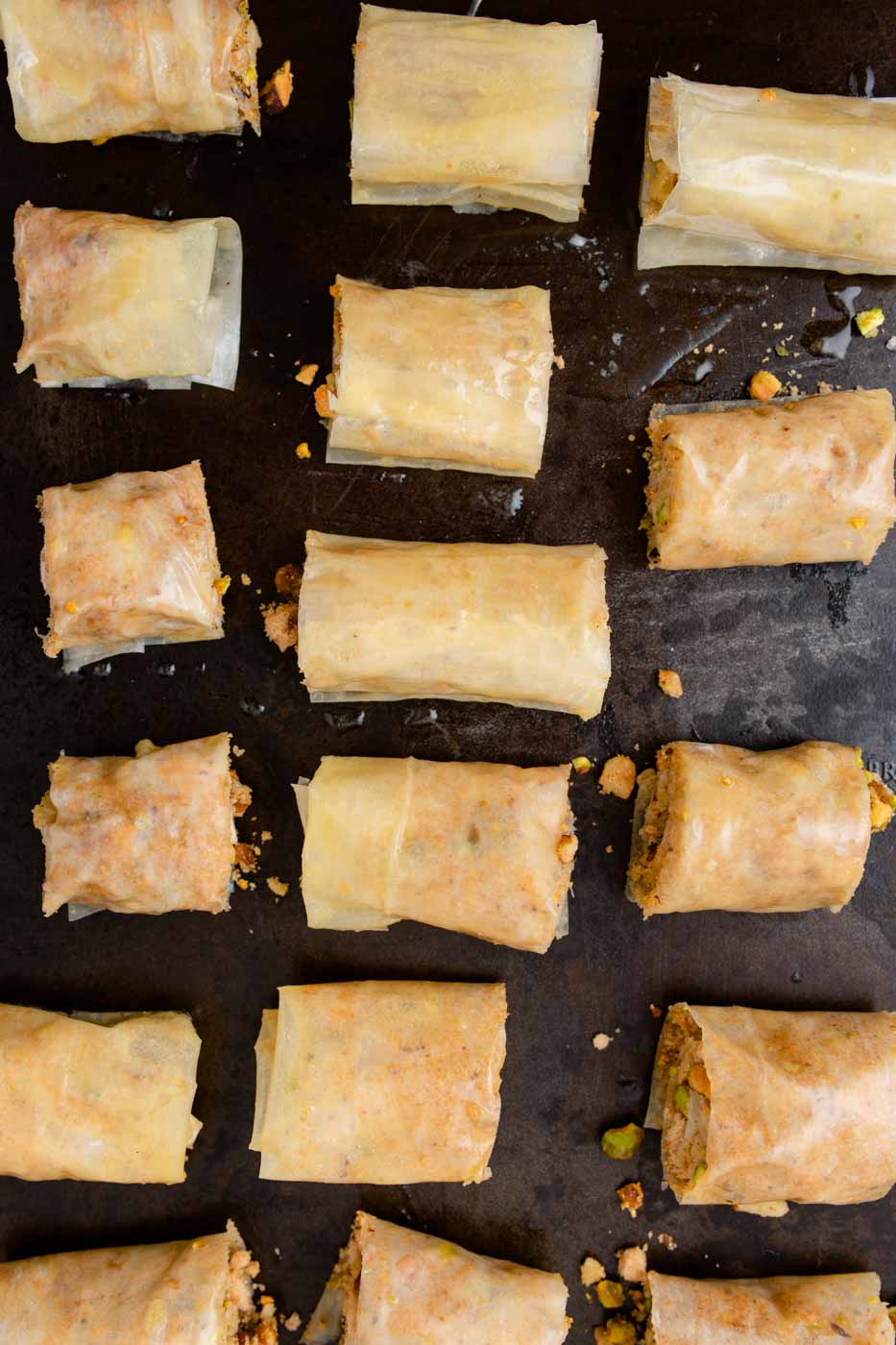 Baklava cut into mini rolls on baking sheet.