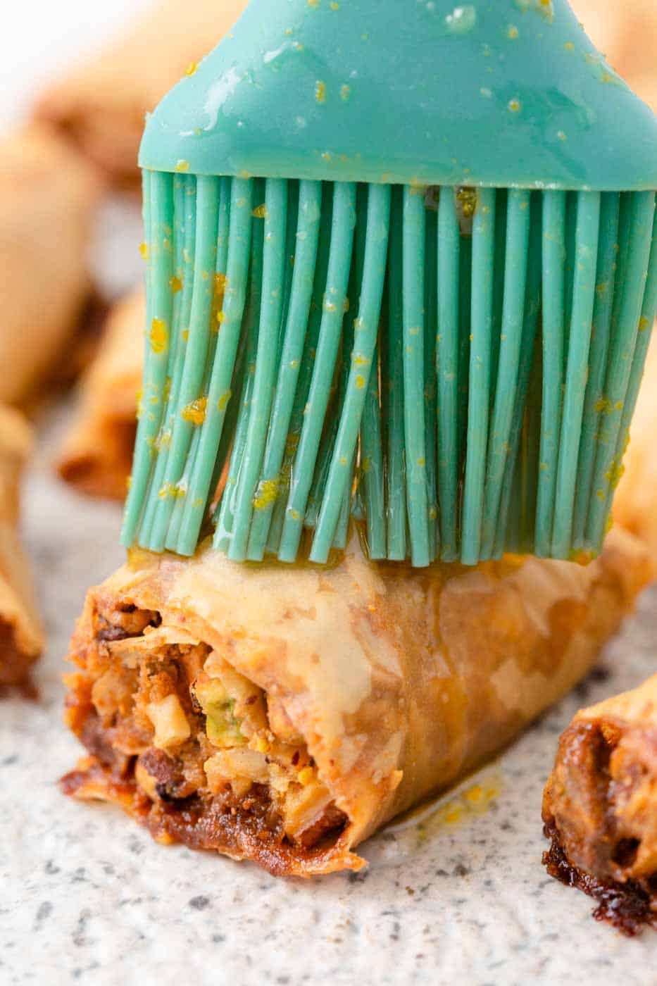 Brushing baklava rolls with honey.