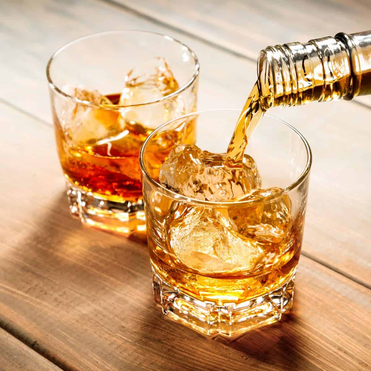 Whiskey being poured into a glass with ice.