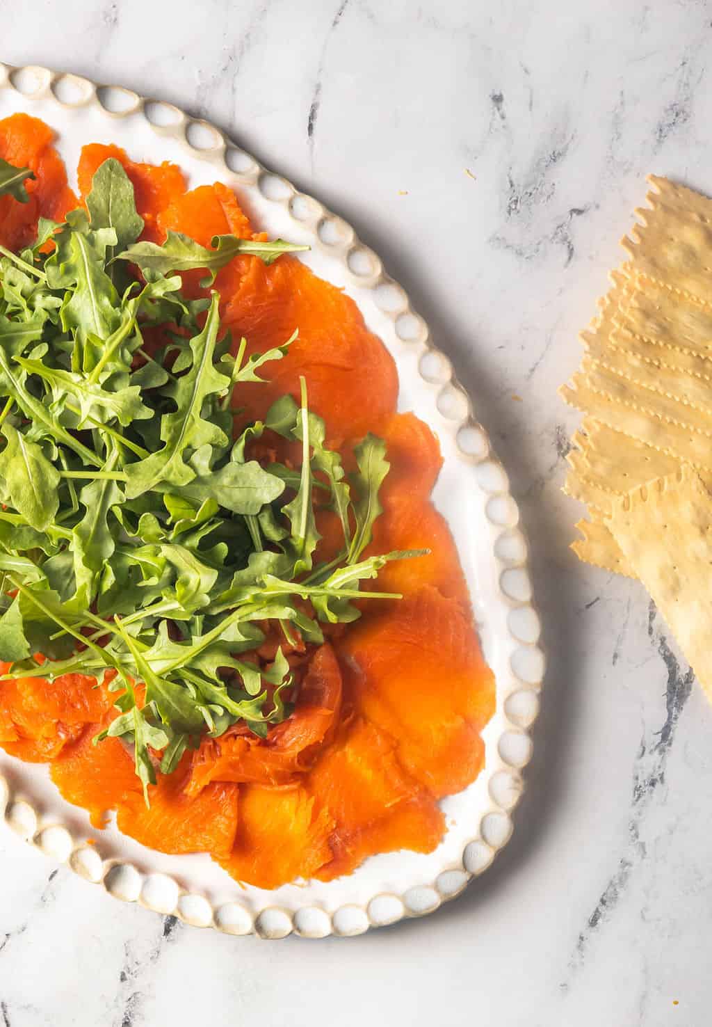 Smoked salmon carpaccio on plate with arugula.