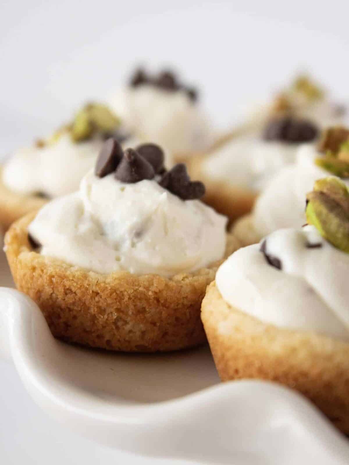 cannoli cookie cups with mini chocolate chips on a white cake platter.
