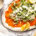 Salmon carpaccio appetizer with arugula and parmesan.