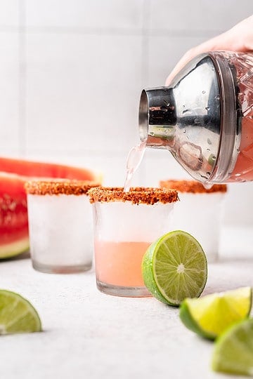 Pouring tequila from cocktail shaker to shot glass.