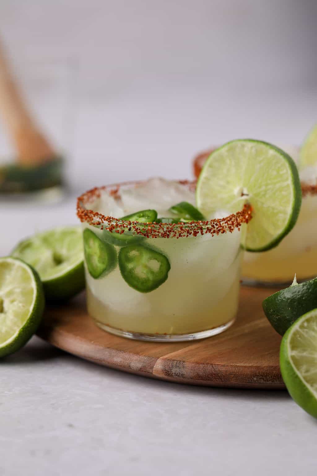 Jalapeno margarita on table with spiced rim and lime.