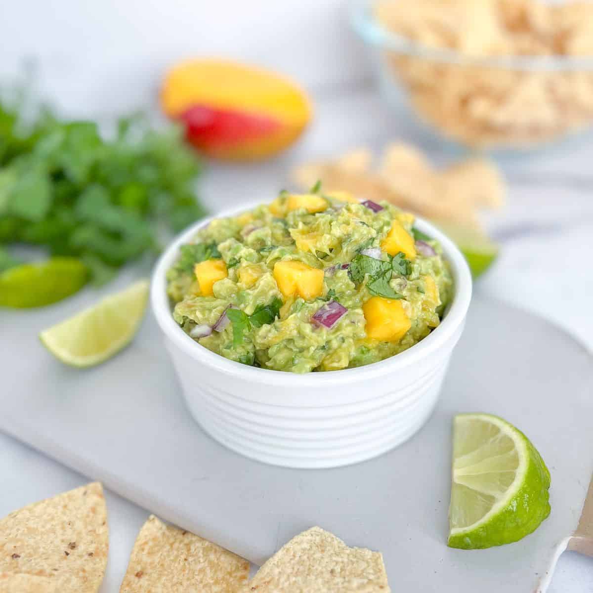 Mango guacamole with lime wedges and tortilla chips.