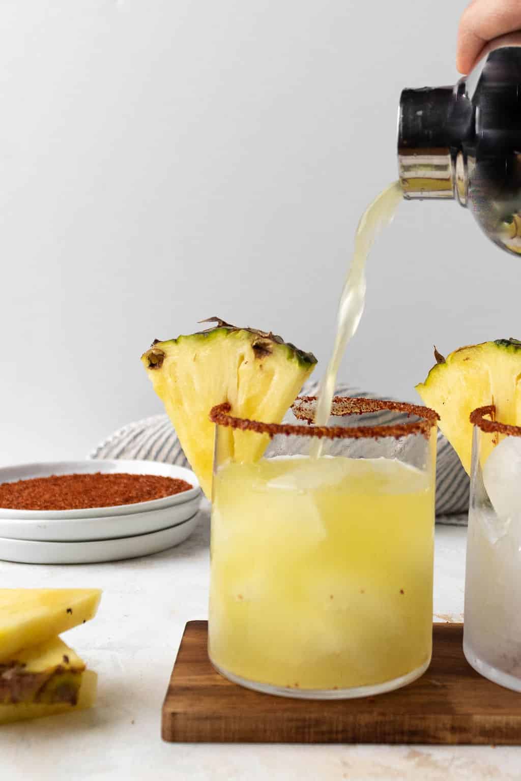 Pouring pineapple jalapeno margarita into glass.