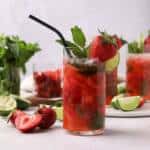 Strawberry mojito in a glass with strawberries, mint and limes.