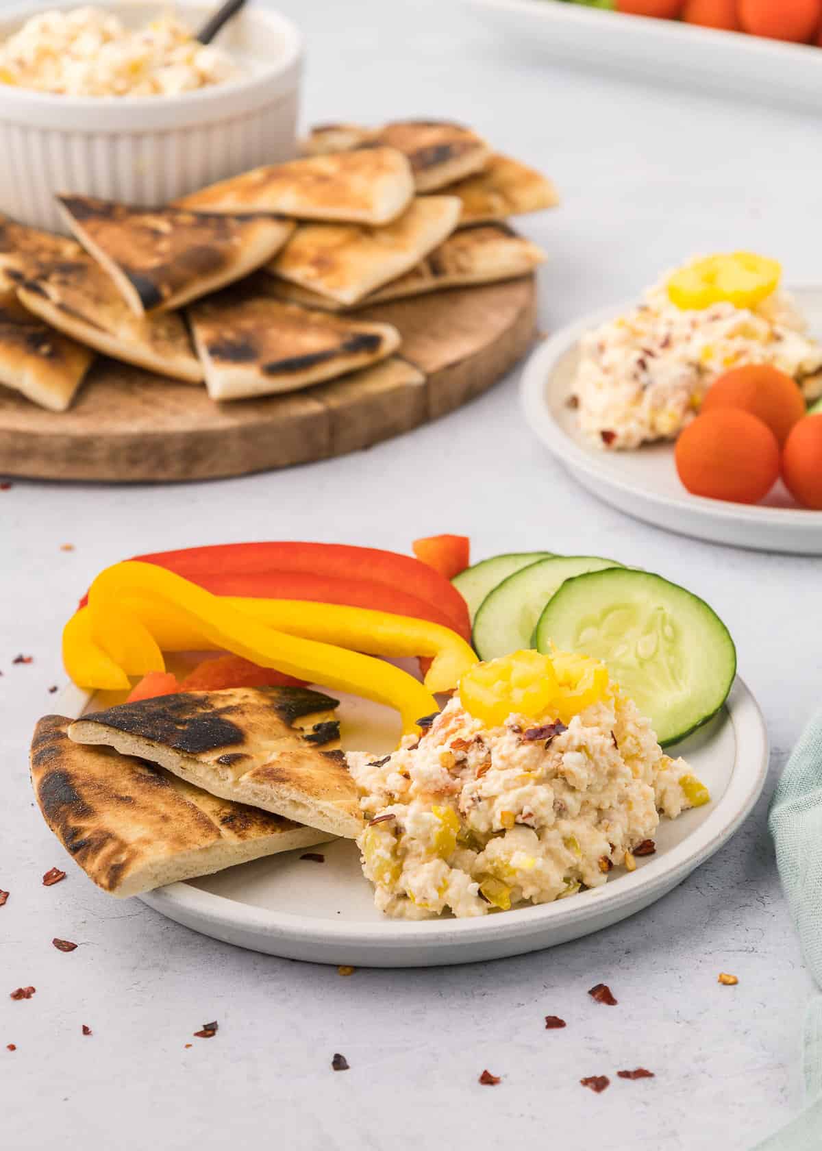 Spicy feta dip with veggies and pita bread on dish.