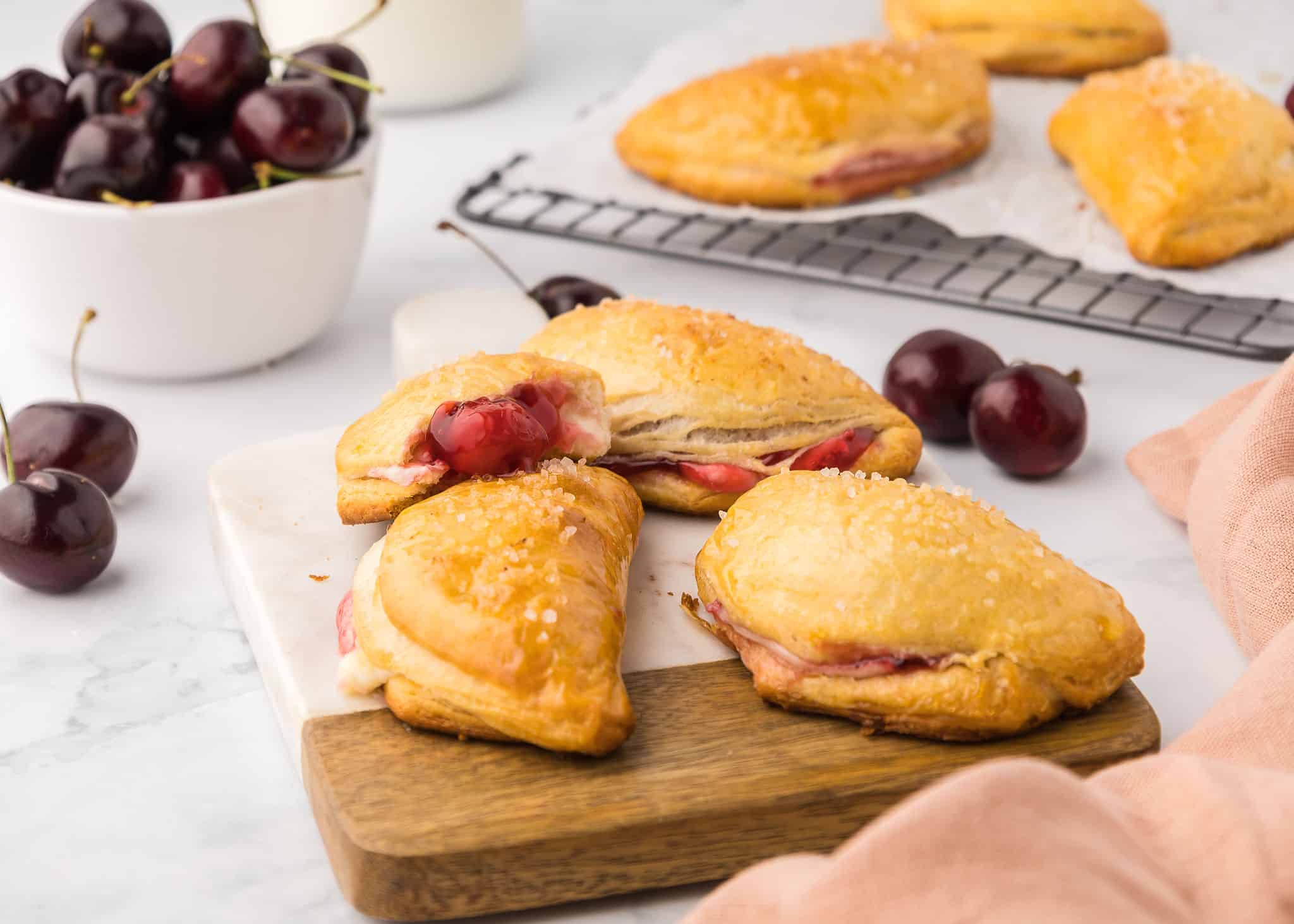 Dessert empanadas on cutting board with cherries.