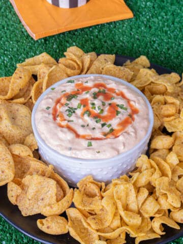 Buffalo onion dip with fritos corn chips around it.