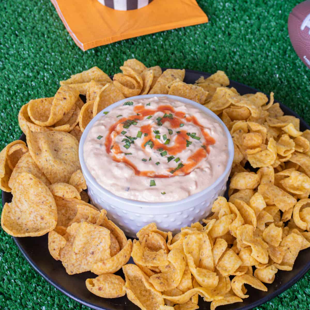 Buffalo onion dip with fritos corn chips around it.