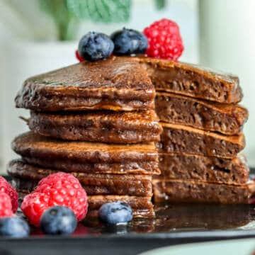 Chocolate milk pancakes on table with berries.