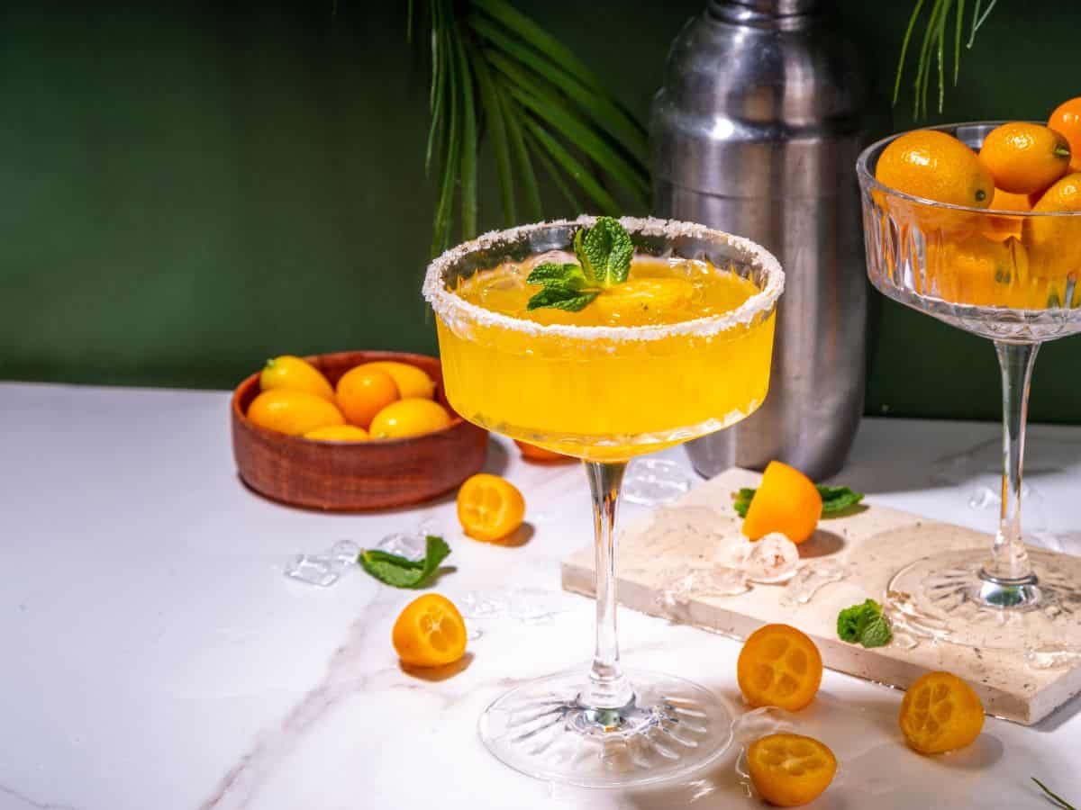 Cocktail using orange liqueur with oranges on table.