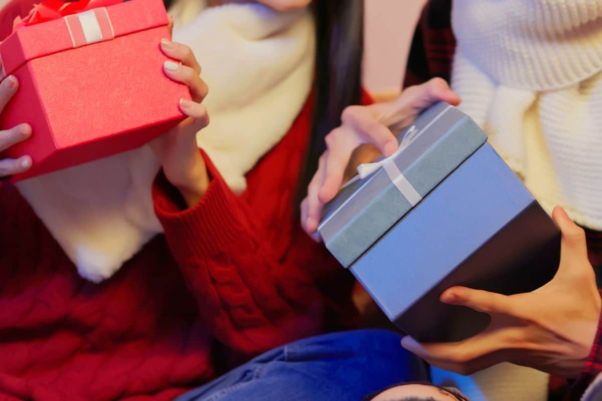 Women holding a blue and red gift box.