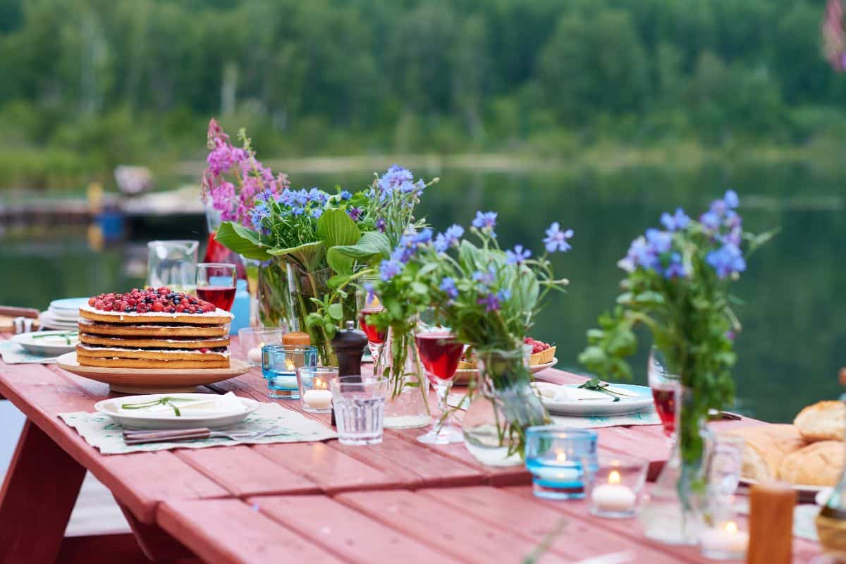 Outdoor picnic table with flowers and cake.
