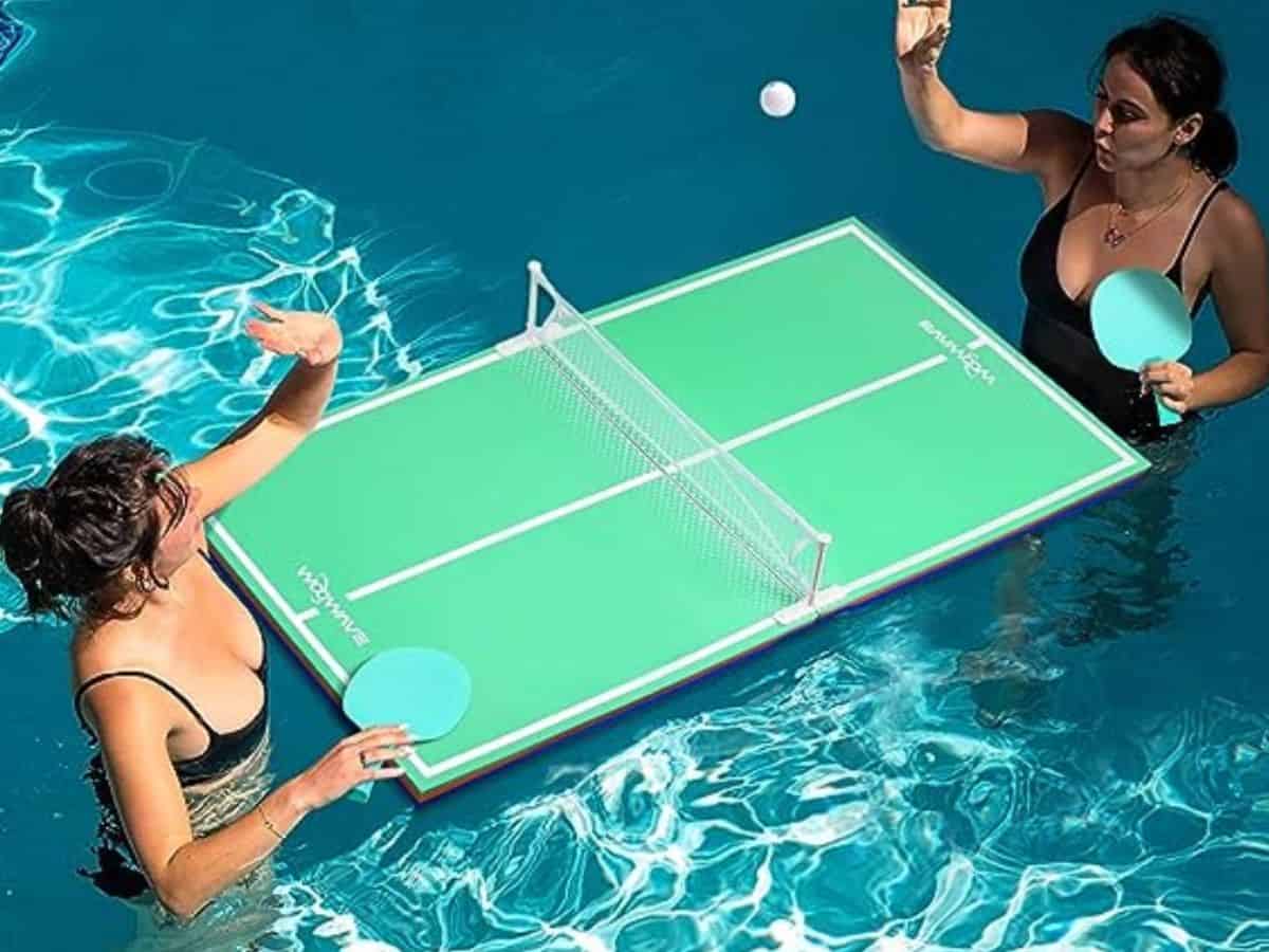 Women playing ping pong in a pool.