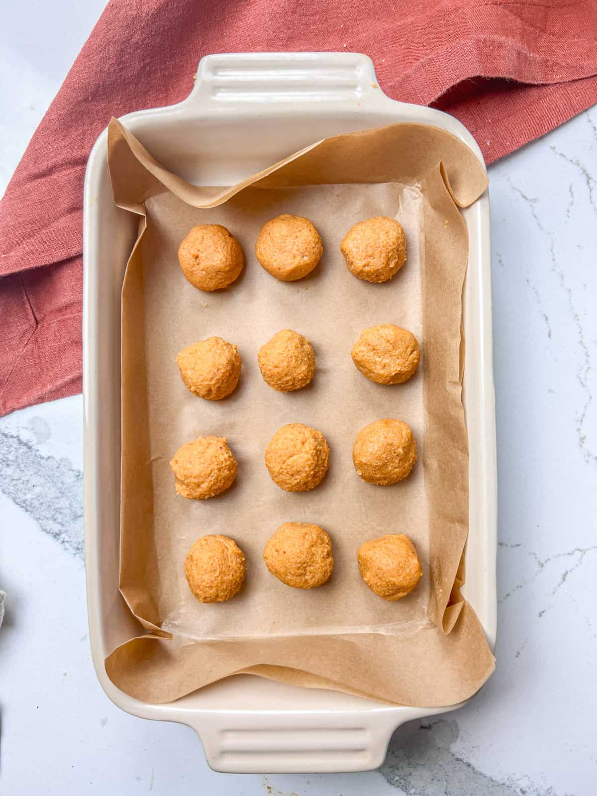 Pumpkin truffles rolled on parchment paper.